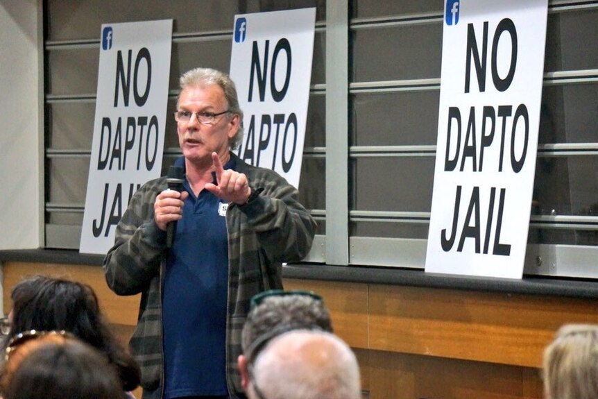A man stands up speaking at a community meeting.