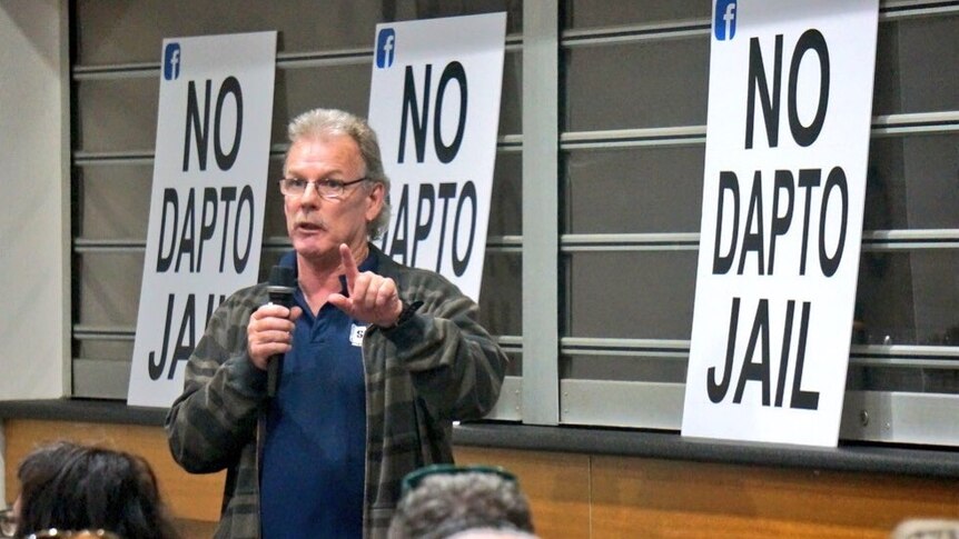 A man stands up speaking at a community meeting.