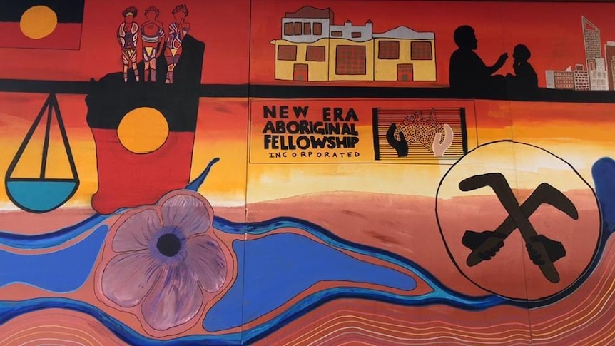 A painting shows Aboriginal flags, flower motifs, various symbols, a sign re "New era Aboriginal Fellowship incorporated"