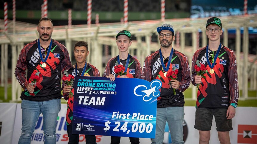 The Australian team at the podium at the World Drone Racing Championships in Shenzhen. They are holding a US$24,000 cheque.