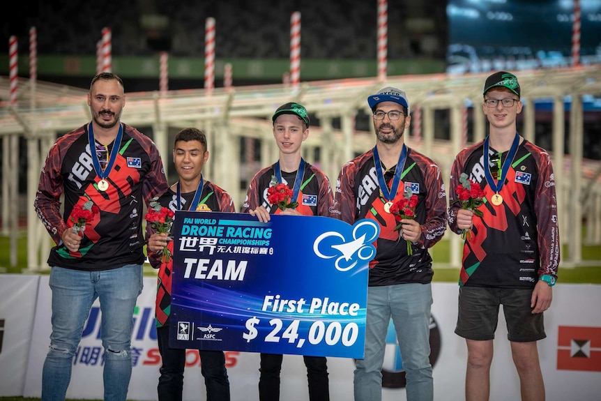 The Australian team at the podium at the World Drone Racing Championships in Shenzhen. They are holding a US$24,000 cheque.