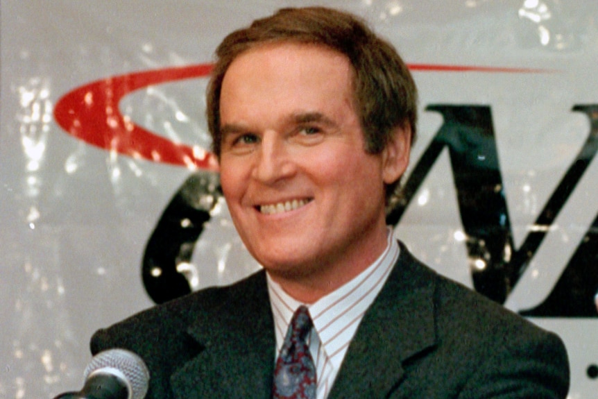 Charles Grodin smiles at the camera while wearing a suit