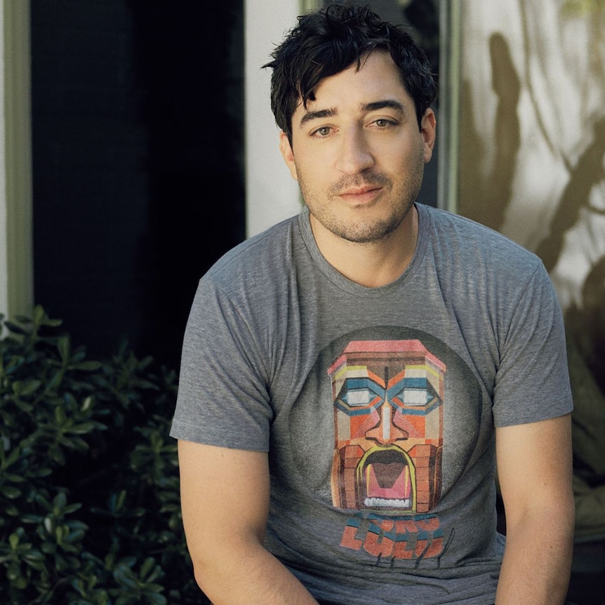 Grizzly Bear frontman Ed Droste sits in his garden wearing a grey t-shirt