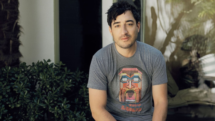 Grizzly Bear frontman Ed Droste sits in his garden wearing a grey t-shirt
