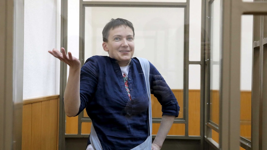 Nadiya Savchenko gestures from inside a glass-walled cage in court.