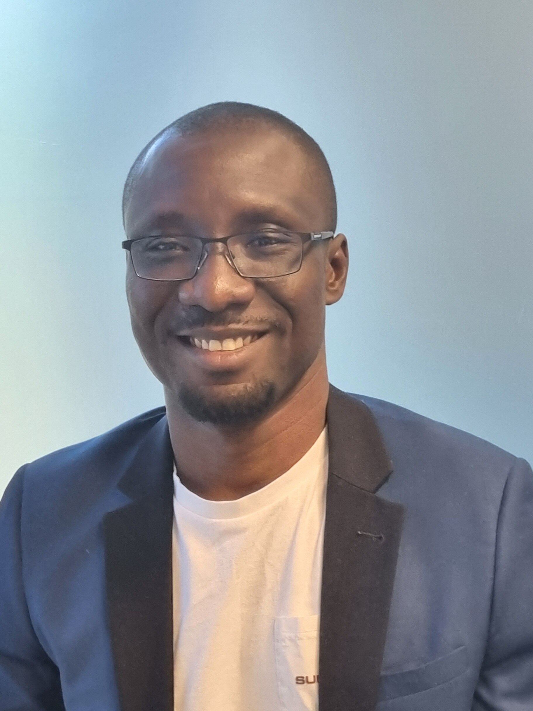 Profile picture of a bespectacled Dr Randy Adjonu smiling.