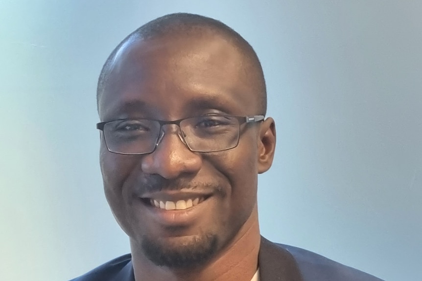 Profile picture of a bespectacled Dr Randy Adjonu smiling.