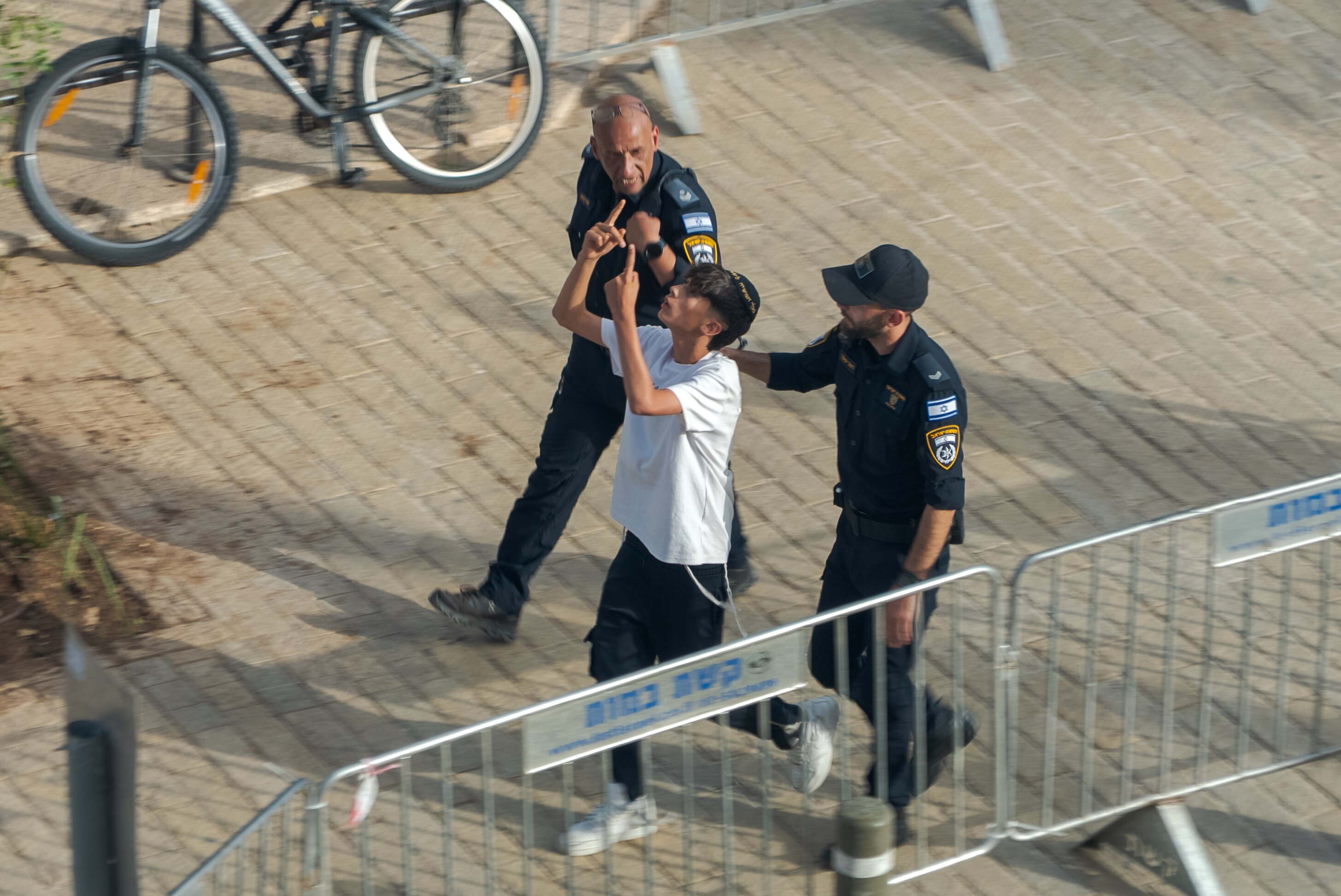 Two guards hold a man in a white shirt 