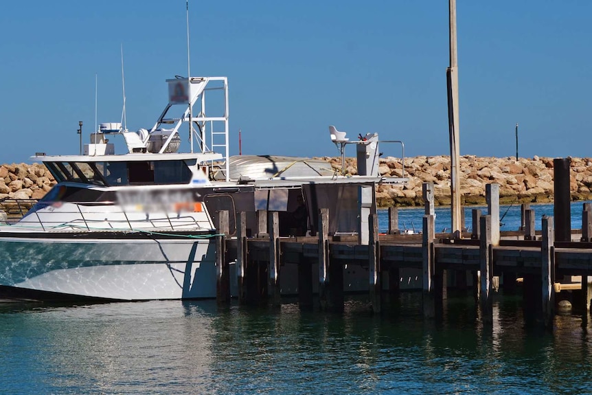 A boat is moored at the end of a pier.