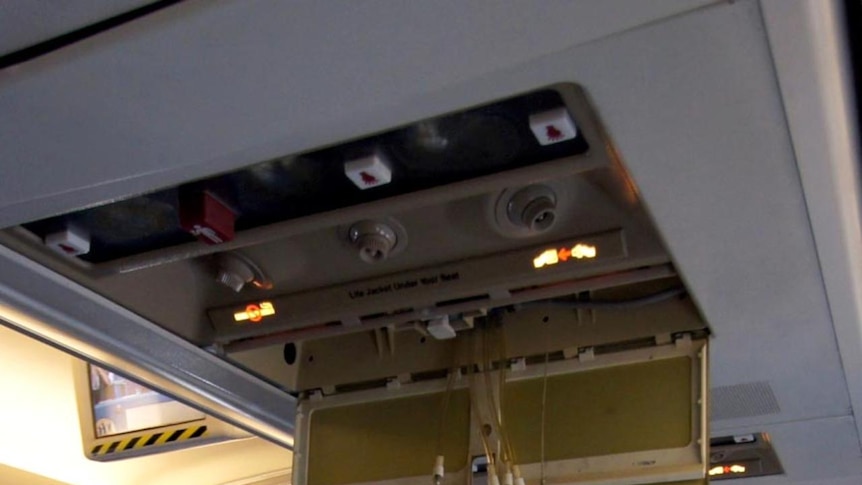 Air masks hang from the ceiling of Qantas Flight QF 670