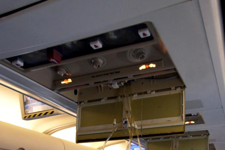 Air masks hang from the ceiling of Qantas Flight QF 670