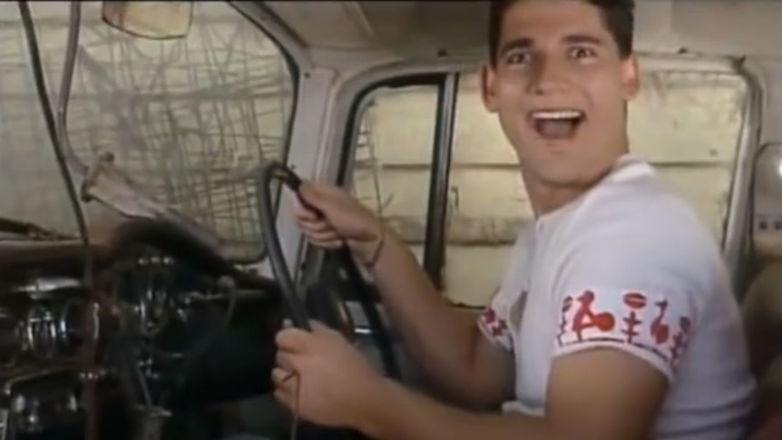 Still of opening credits of Full Frontal, shows Eric Bana smiling while driving a car