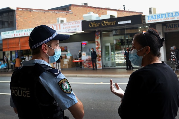 A police officer speaks with a woman in front of a shopping strip
