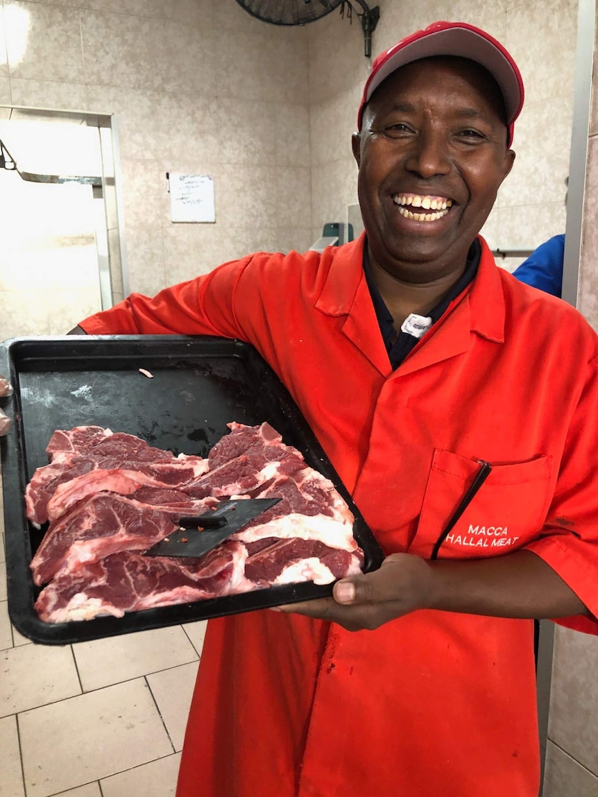 Butcher Abukar Hersi holds a tray of camel meat.