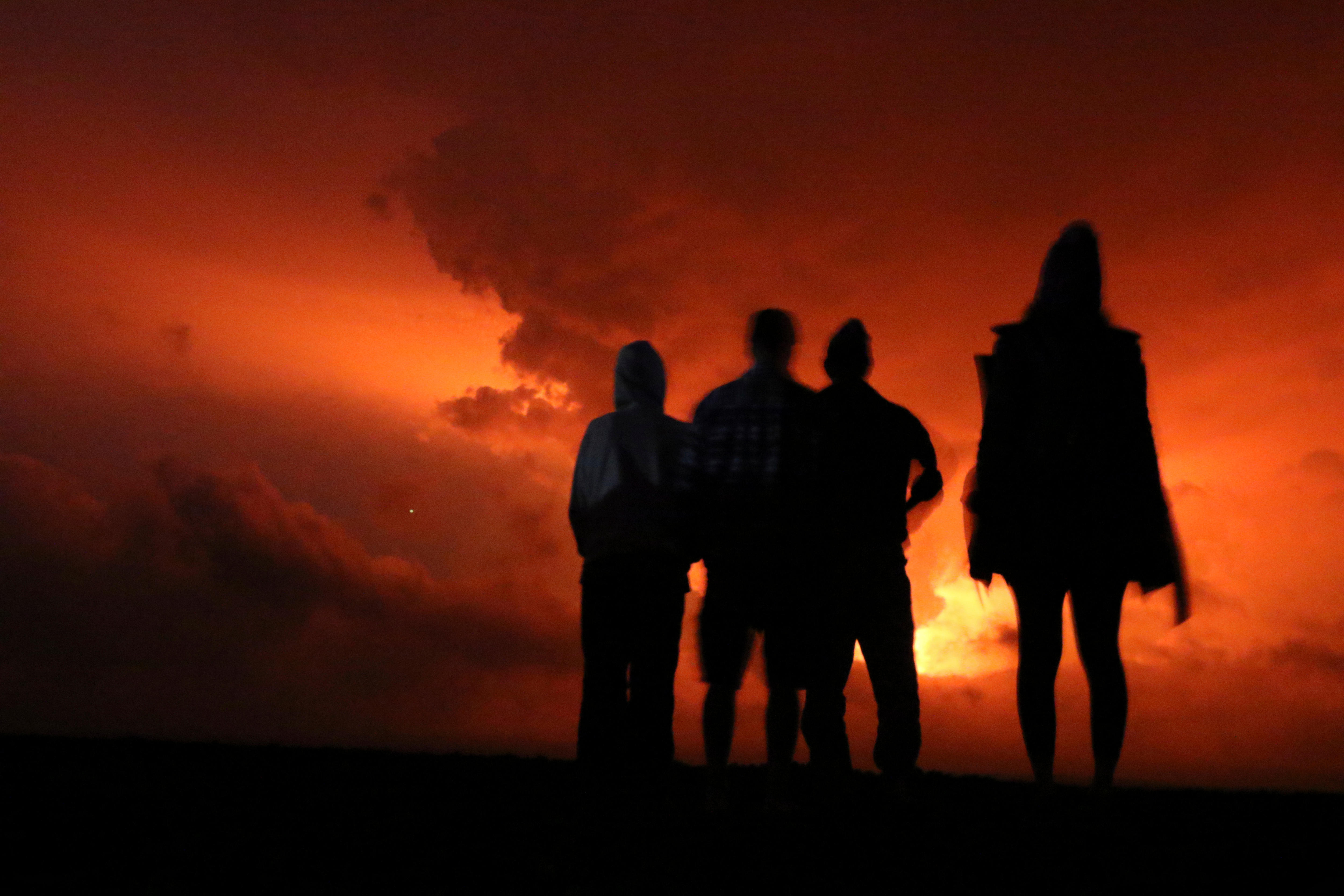 Oamenii urmăresc strălucirea lavei care erupe din vulcan