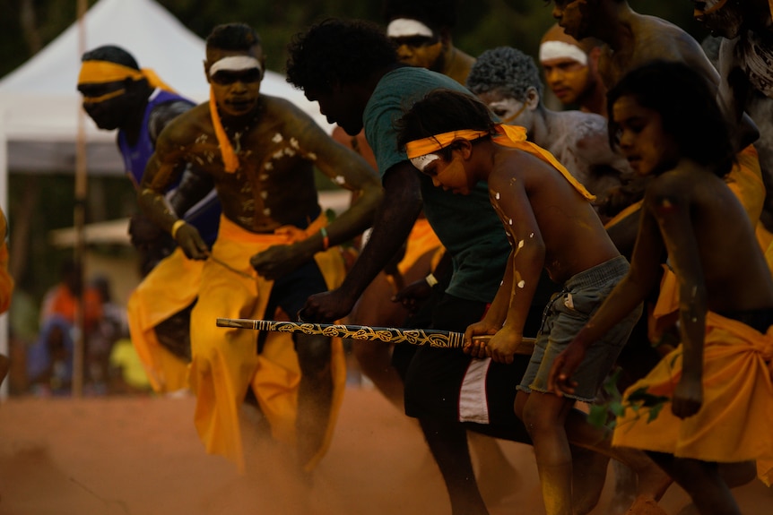 Dancers in traditional Indigenous dress perform in a group.