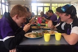 School students are having lunch in a canteen.