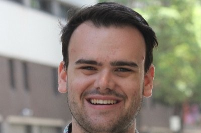 A young man standing on the street smiles