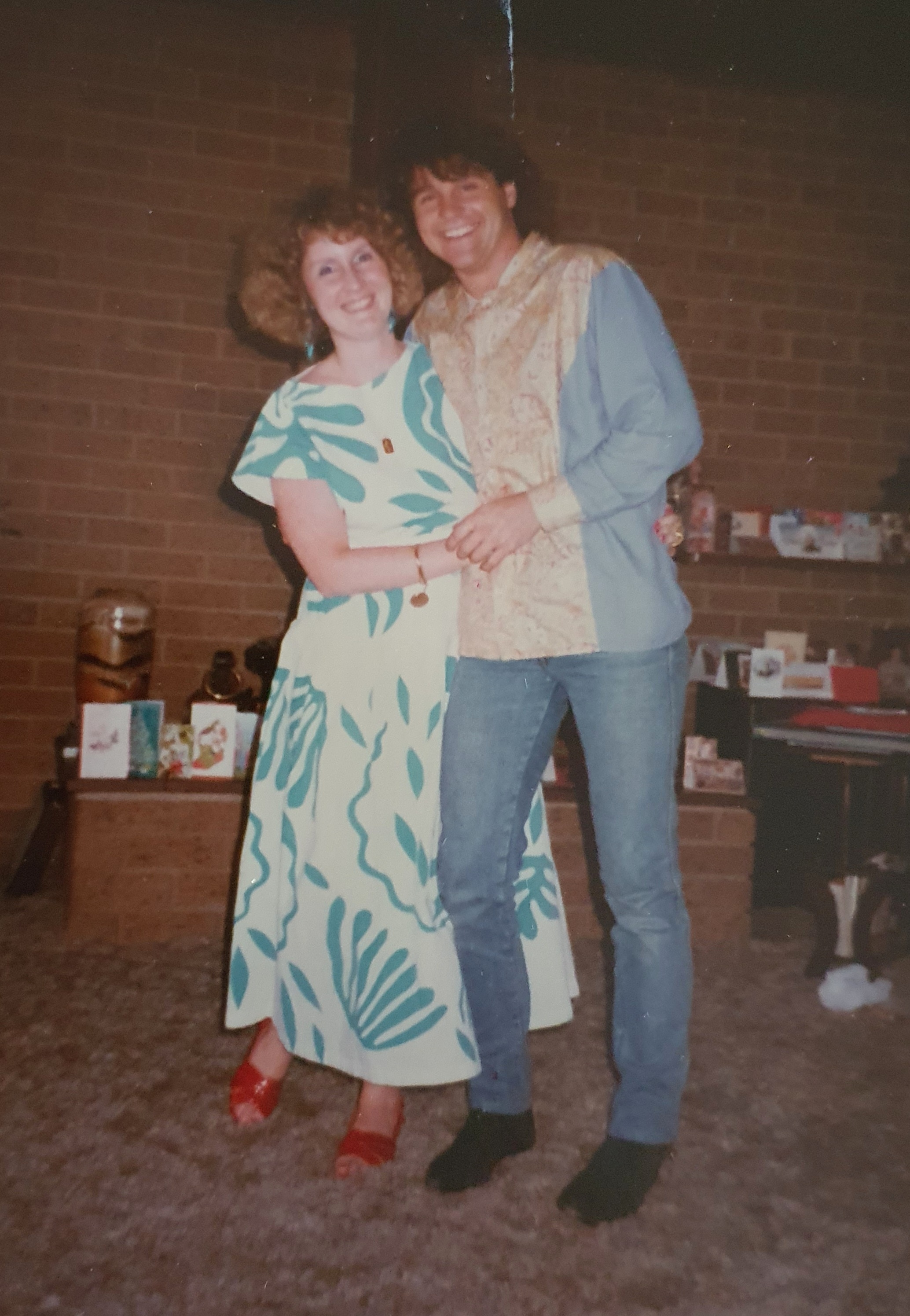 A brother and sister stand together smiling.