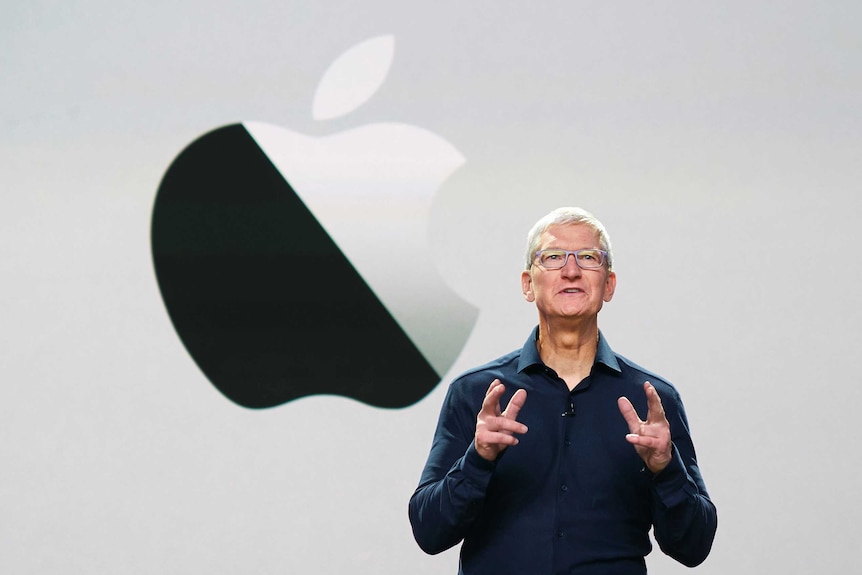 Tim Cook stands in front of a screen with an Apple logo.