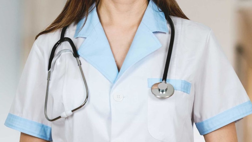 A female in a doctor's uniform stands with a stethoscope around her neck.