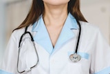 A female in a doctor's uniform stands with a stethoscope around her neck.