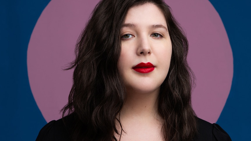 Headshot of singer Lucy Dacus standing in front of a purple circle