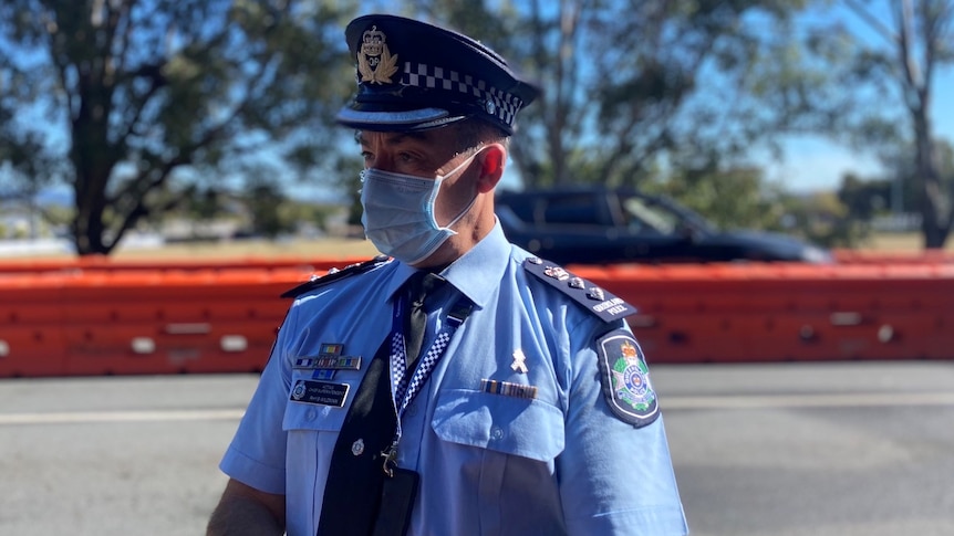 A police officer wearing a blue mask against orange barriers.