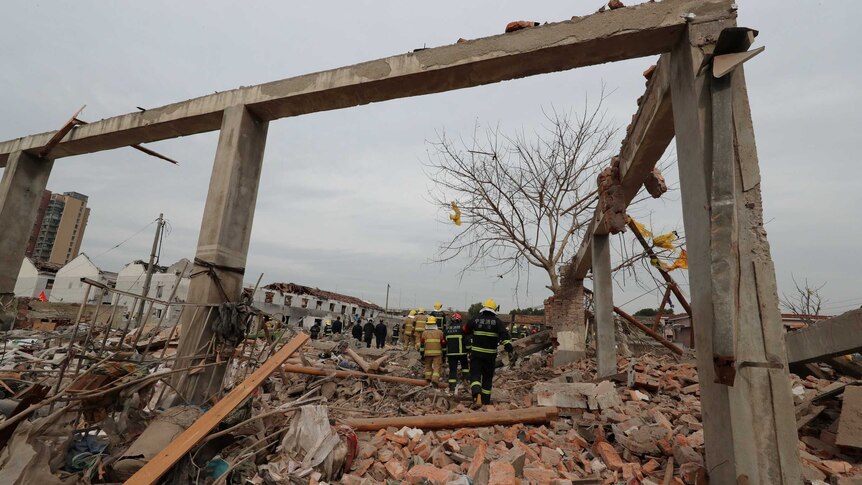 Rescue workers stand beneath the frame of a destroyed building in China.