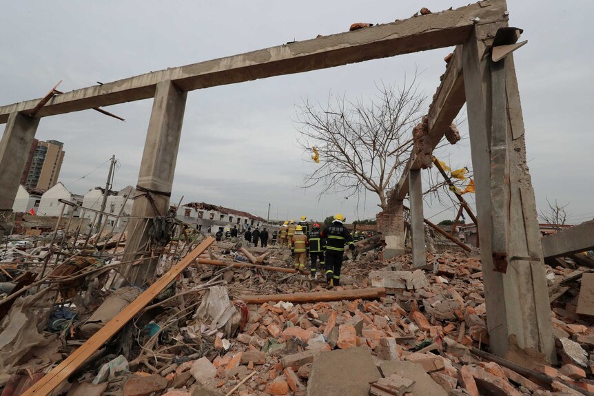 Rescue workers stand beneath the frame of a destroyed building in China.