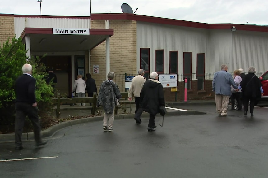 A small crowd of people walking into a hall for the public memorial of one of the victims of the suspected mushroom poisoning.