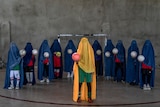 An Afghan women's soccer team poses for a photo wearing burqas and holding footballs.