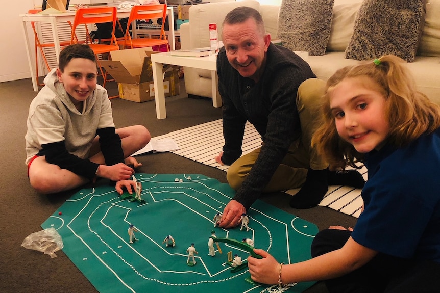 Tweenage boy and girl playing indoor cricket game with dad  