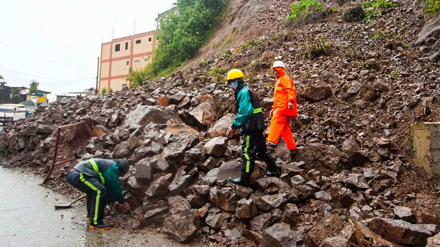 Workers clear debris from a landslide that occurred at the height of Typhoon Utor