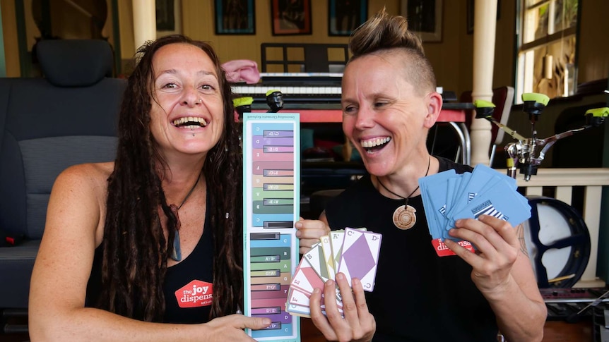 Two ladies holding playing cards with music notes on them.