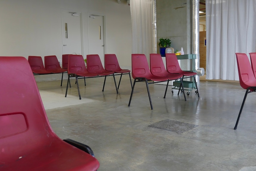 Burgundy chairs are lined inside an empty retail office space.