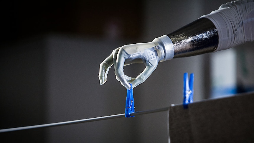 A bionic arm putting a peg on a clothesline