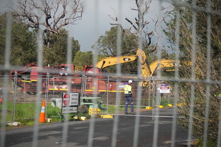 Bulldozers and machinery observed through a gate
