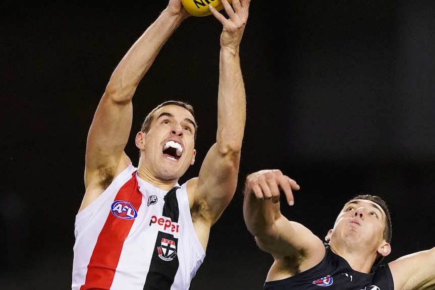 Max King's mouth is open as he stretches above his head to mark the ball. His defender is falling behind him.