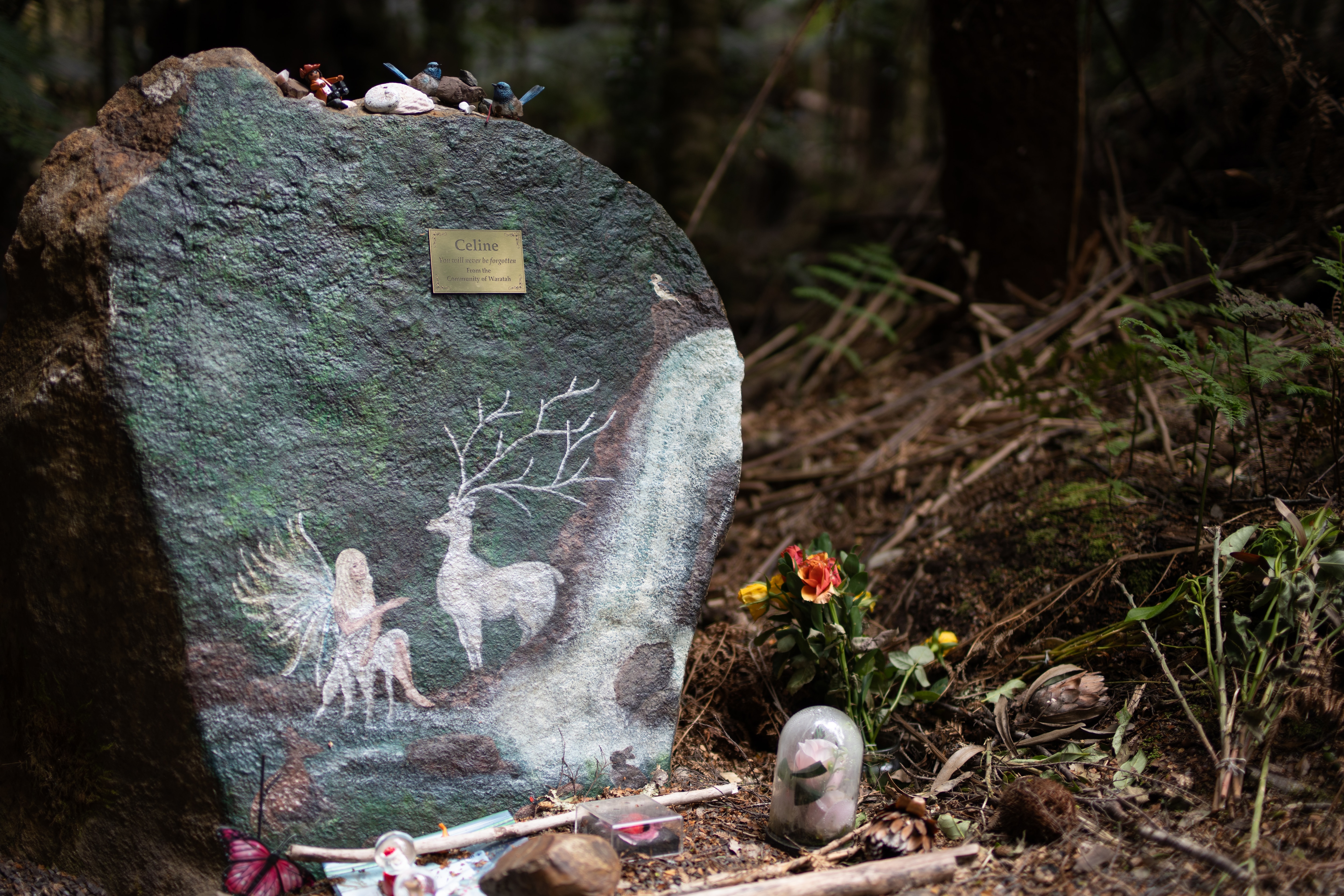 Memorial com flores entre árvores.