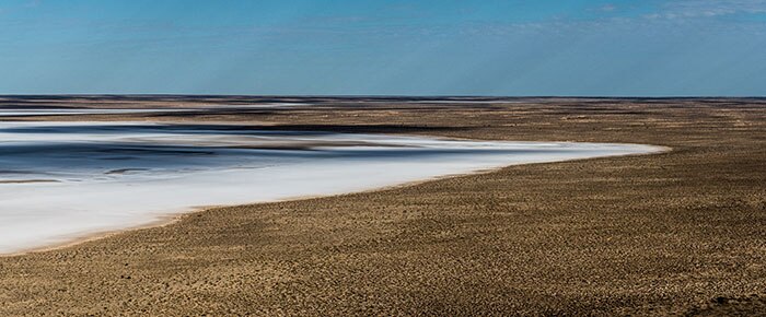 A blue horizon, brown sand and a mix of blues and whites.