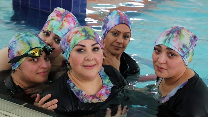 Five women wearing headgear in a  swimming pool