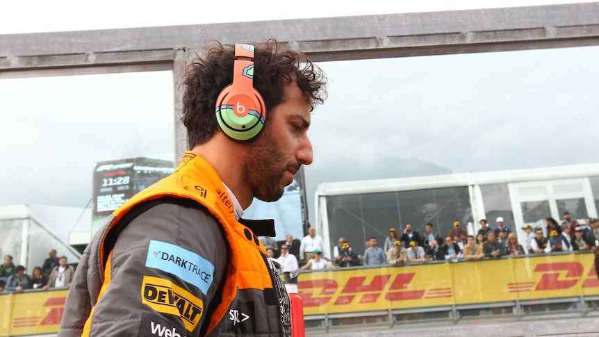 Race driver with headphones walks along the pit wall. 