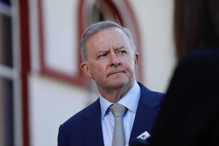 Anthony Albanese looks concerned, the walls of a church stand out of focus behind him.