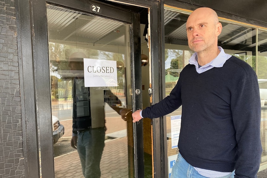 A man closing a door with a closed sign on it.