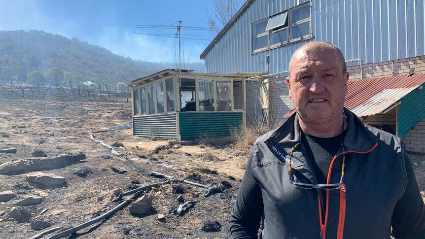 Ballandean resident Rob Davidson stands at the burnt remains of a shed and his vineyards.