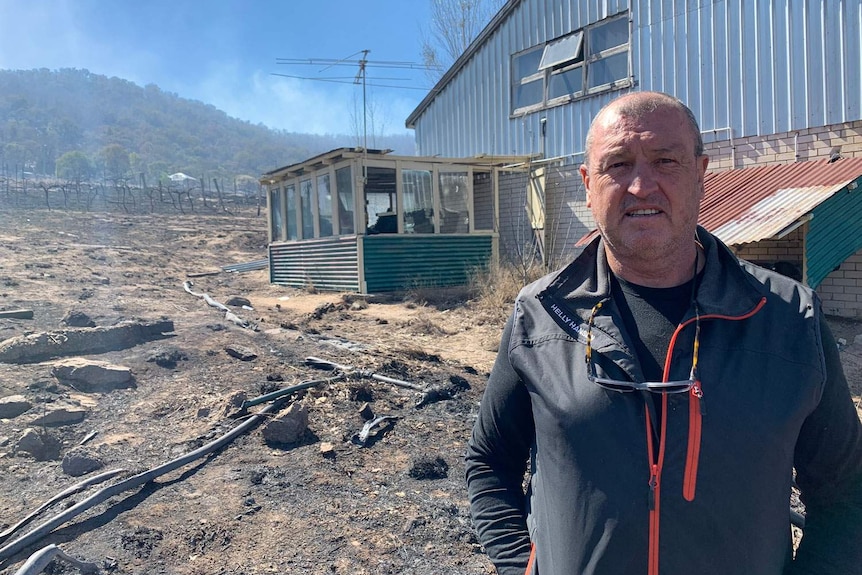 Ballandean resident Rob Davidson stands at the burnt remains of a shed and his vineyards.