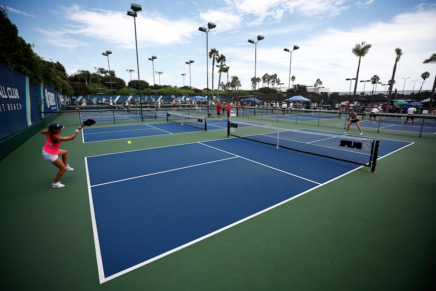 Players play on multiple pickleball courts.