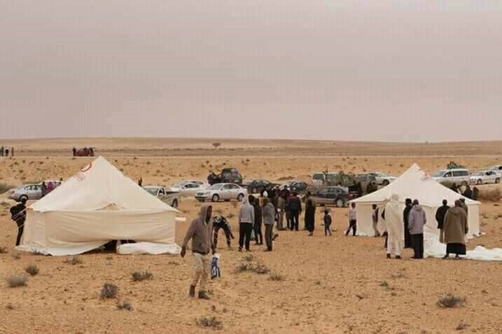 People walk among tents in the desert