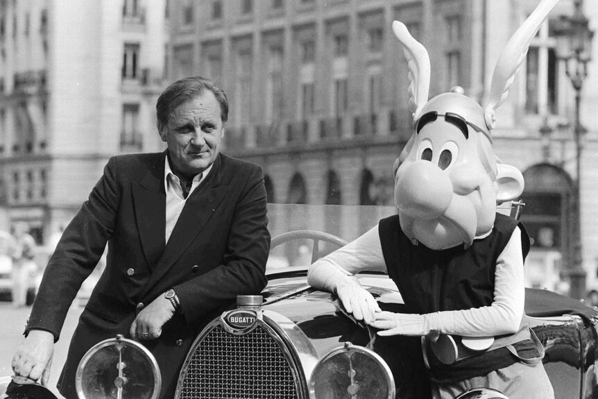 French author and illustrator Albert Uderzo poses leaning on an old car with a character Asterix in Paris.